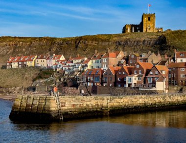Yukarıdaki St. Mary Kilisesi. Whitby Limanı 'nın girişindeki rıhtımdaki evler Birleşik Krallık' ın Kuzey Yorkshire 'ı..