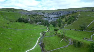 İngiltere 'nin kuzeyindeki Kuzey Yorkshire Dales' deki Malham Koyu 'nun havadan görüntüsü. Malham Koyu, 12.000 yıldan uzun bir süre önce buzul çağından eriyen suyu taşıyan bir şelalenin oluşturduğu büyük kıvrımlı bir kireçtaşı oluşumudur..