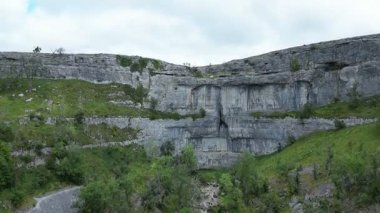 İngiltere 'nin kuzeyindeki Kuzey Yorkshire Dales' deki Malham Koyu 'nun havadan görüntüsü. Malham Koyu, 12.000 yıldan uzun bir süre önce buzul çağından eriyen suyu taşıyan bir şelalenin oluşturduğu büyük kıvrımlı bir kireçtaşı oluşumudur..