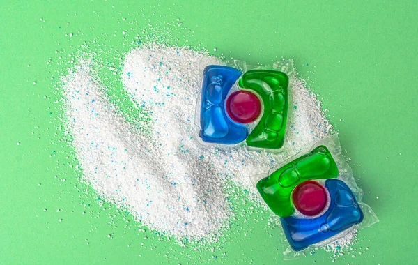 Washing powder and capsules for washing on a green background. High quality photo