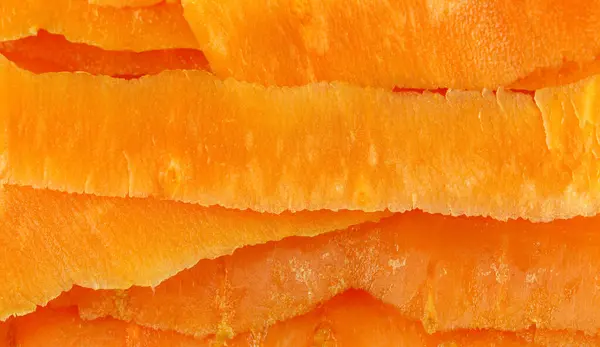 Dilimlenmiş havuçların yakın plan görüntüsü, canlı turuncu renklerini ve dokulu yüzeylerini gösteriyor. Dilimler üst üste bindirilip görsel olarak ilginç bir kalıp oluşturuluyor.. 