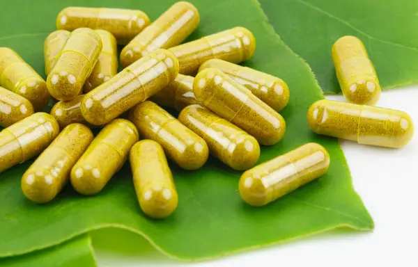Şeffaflıkta zerdeçal tozu Sert Jelatin Kapsülleri Yeşil Doğal Yapraklar Beyaz Arkaplanda.