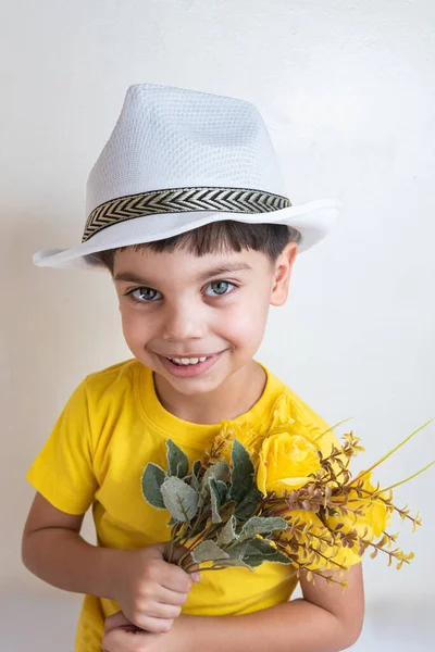 Cute and happy boy with yellow t-shirt - With white hat on head holding flowers