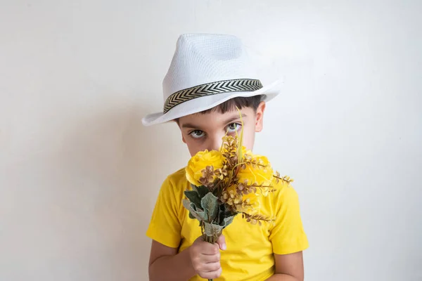Cute and happy boy with yellow t-shirt - With white hat on head holding flowers