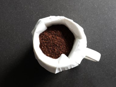 Kahve içinde kahve telvesi, siyah granit tezgahta filtre var.