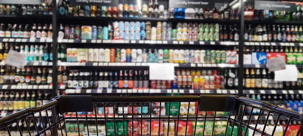 百貨店のトロリーが付いているアルコール店の抽象的なぼやけたイメージ ショッピングカートに焦点を当てる — ストック写真