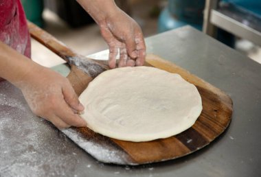 Elleri ahşap tepside pizza hamuru hazırlıyor.