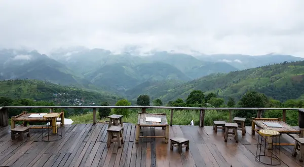 stock image Wooden terrace with the natural mountain view covered with clouds and fog