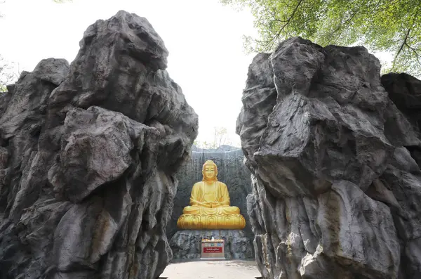 Die Große Goldene Buddha Statue Mit Wasserfall Und Steinmauer Hintergrund lizenzfreie Stockfotos