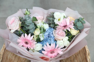 Gri fayanslı zemin üzerinde sepette karışık renkli çiçek buketi