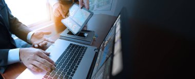 Bir tablet ve dizüstü bilgisayarda gösterilen verileri tartışan iş adamları, sunum ve analize odaklandılar