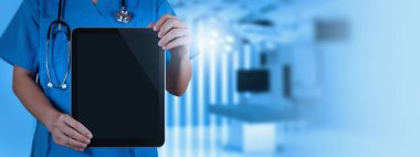 Mavi önlüklü bir sağlık çalışanı, modern bir tıbbi ortamda teknolojiyi gösteren boş bir dijital tablet tutuyor.