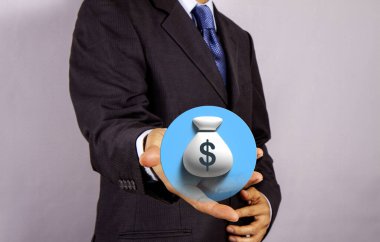 Takım elbiseli bir işadamı, bir dolar işareti ile sanal para çantası ikonunu sunuyor. Finans, yatırım ya da iş karını simgeliyor..
