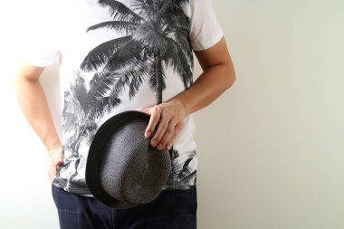  Üzerinde siyah palmiye ağacı izleri olan beyaz bir tişört ve yanında siyah bir hasır şapka taşıyan sıradan bir yaz kıyafeti giymiş biri. Açık renkli arka planda rahat bir poz, rahat ve tropik bir tatil havasını çağrıştırıyor. Onlar için ideal.