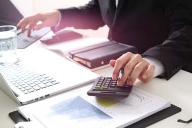  Finansal tablolar, raporlar, belgeler, veri analizi, finans ve ofis çalışmalarını gösteren hesap makinesi ve dizüstü bilgisayar kullanarak takım elbiseli işadamlarının yakın çekimleri.