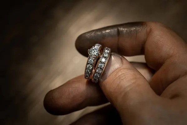 stock image Closeup of a diamond wedding ring and dirty jeweller hands holding it