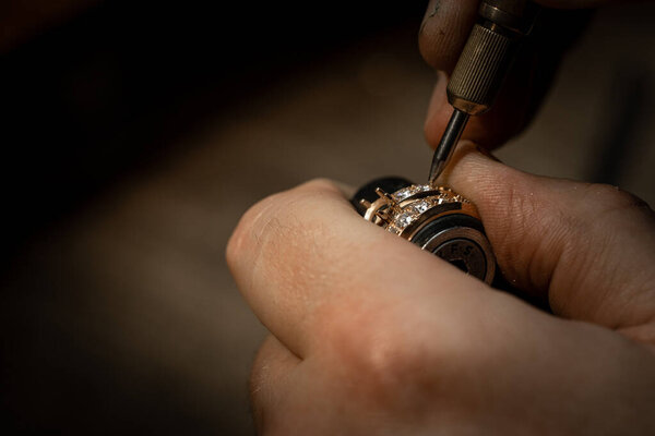 Jeweler puts diamond to golden wedding luxury ring.