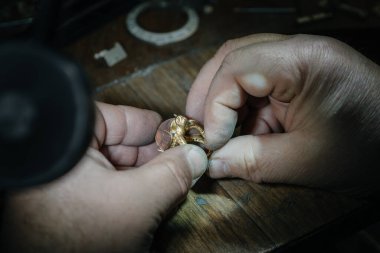 Master jeweler produces a gold ring with a big pink stone clipart