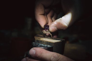 Mücevher ustası gelecekteki mücevherlere elle mücevher yerleştirir. Profesyonel aletlerle mücevher yapmak için çalışma masası. Kuyumcunun masasında Sapphire elmas yüzüğü