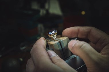 Mücevher ustası gelecekteki mücevherlere elle mücevher yerleştirir. Profesyonel aletlerle mücevher yapmak için çalışma masası. Kuyumcunun masasında Sapphire elmas yüzüğü
