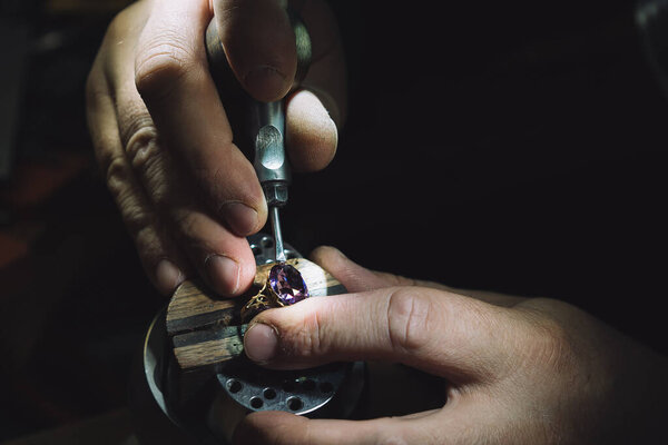 master of jewelry manually inserts gems into the frame of future jewelry. Working desk for craft jewelry making with professional tools. Sapphire diamond ring on the jeweler's desktop