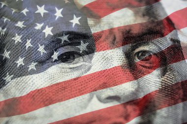 Closeup Benjamin Franklin face on USD banknote with USA flag and stock market chart graph for currency exchange and global trade forex concept.