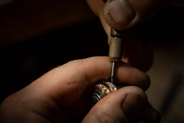 Jeweler puts diamond to golden wedding luxury ring.