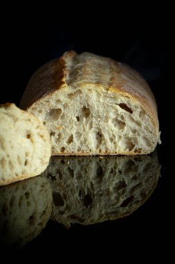 Siyah ayna mutfak masasında taze pişmiş ciabatta ekmeği. Masanın üzerindeki fotoğrafı kapat.