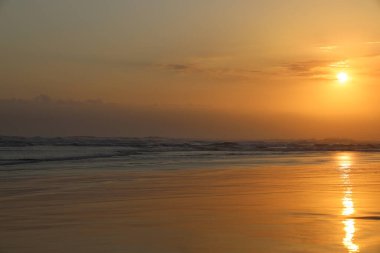 Akşam güneşinin ışığı hala Parangtritis sahilinde, Yogyakarta 'da görülebilir. Gökyüzü sarardı. Işığın yansımaları ve gölgeleri sahildeki ıslak kuma yansıyor. Parang Tritis sahilinde alacakaranlık, Yogyakarta Endonezya