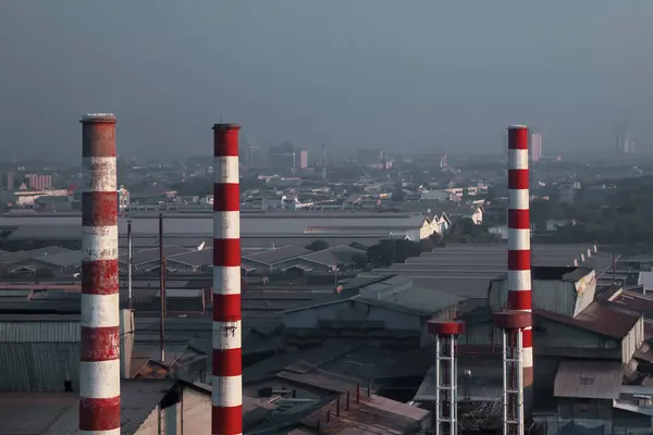 Surabaya kentindeki sanayi bölgesinin bir kısmında, fabrikaların hala sakinlerin evleri arasında durduğu ve bacaların yakında ses ve yoğun duman yayacağı görülebiliyor..