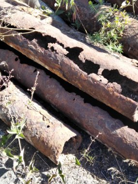 Çimlerde paslı borular yığını. Aşınma. Endüstriyel Terk Etme.