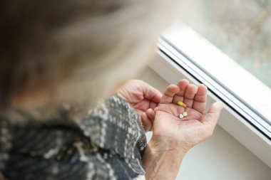 Elinde haplar olan yaşlı bir kadın.