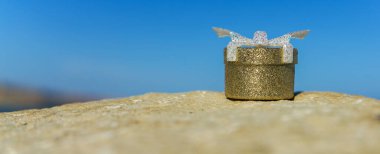 Mavi gökyüzüne karşı çakıl taşı üzerine yerleştirilmiş yüzük kutusu