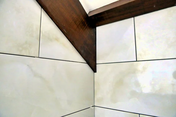 新铺的意大利大理石效果墙砖被切割 以适应支撑倾斜天花板的梁周围 — 图库照片