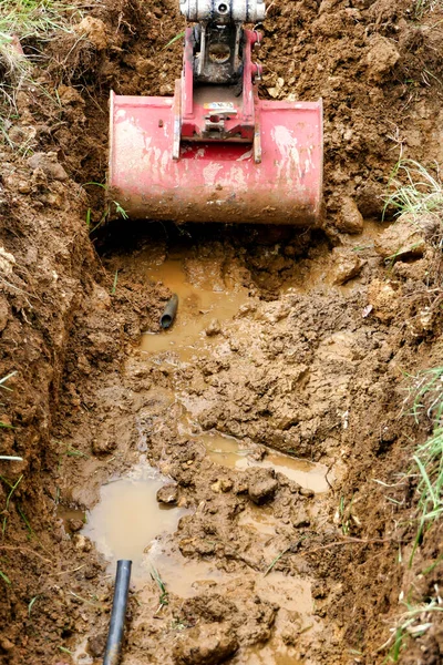 掘削機は 水道管の壊れた部分を公開するために土壌を掘ります — ストック写真