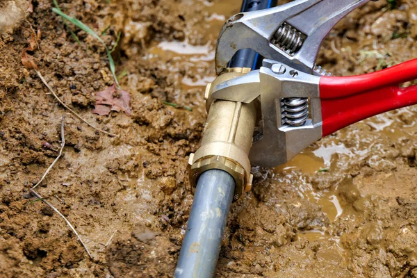 調節可能なスパナを使用して 新旧水道管に真鍮ジョイントコネクタを取り付ける作業者 — ストック写真