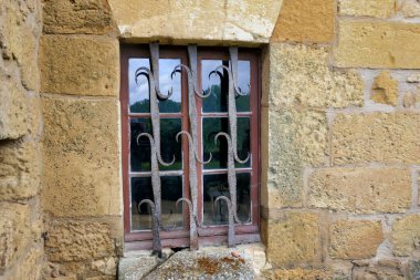 Medieval mullioned window with an ornate wrought iron security grill clipart