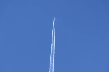 Girdap, güzel mavi gökyüzünü ikiye ayıran alçaktan uçan bir jet uçağının dumanı altında.