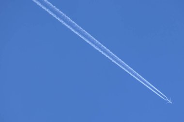 Girdap, güzel mavi gökyüzünü ikiye ayıran alçaktan uçan bir jet uçağının dumanı altında.