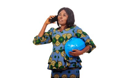 a woman engineer in traditional clothes standing on a white background with safety cap talking on the mobile phone.