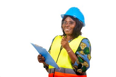 Geleneksel giysiler içinde güzel bir bayan mühendis beyaz arka planda duruyor elinde bir pano ve kameraya bakıp gülüyor..