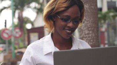 Sınıftan sonra gözlüklü genç bir öğrenci gülümserken dizüstü bilgisayarla araştırma yapıyor.