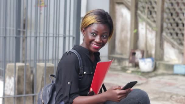 Joven Estudiante Sentado Mochila Tratando Manipular Teléfono Móvil Mientras Sonríe — Vídeo de stock