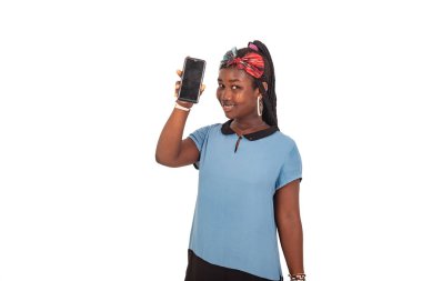 Yukarıda duran güzel bir genç kız beyaz arka planda cep telefonunun gülümsediğini gösteriyor..