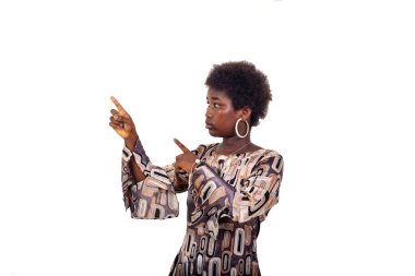 Beyaz arka planda duran genç bir kız parmaklarını kenarı işaret ediyor..