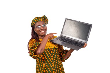 Gözlüklü güzel, olgun bir kadın beyaz arka planda durup dizüstü bilgisayarına bakıp gülümseyen kameraya bakıyor..