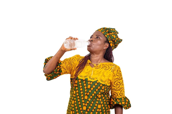 白い背景に立つ伝統的な服を着た大人の美しい女性がペットボトルから水を飲み — ストック写真