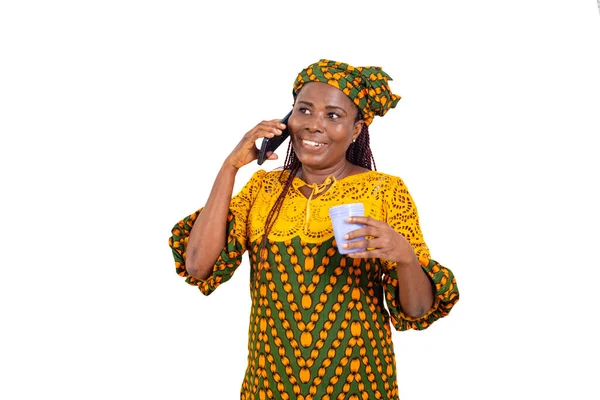 一位穿着传统服装的漂亮而成熟的女商人 拿着奶瓶笑着站在白色的背景下 一边用手机交谈 — 图库照片