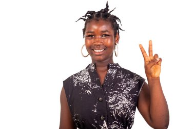 Beyaz arka planda duran geleneksel örgülü genç kız iki parmağını gülümserken gösteriyor..