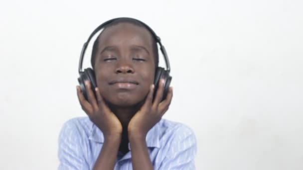 流行音乐 开心的笑着的新生儿在白色背景的耳机里听音乐 可爱的小男孩带着大耳机 有感情的搞笑系列 — 图库视频影像